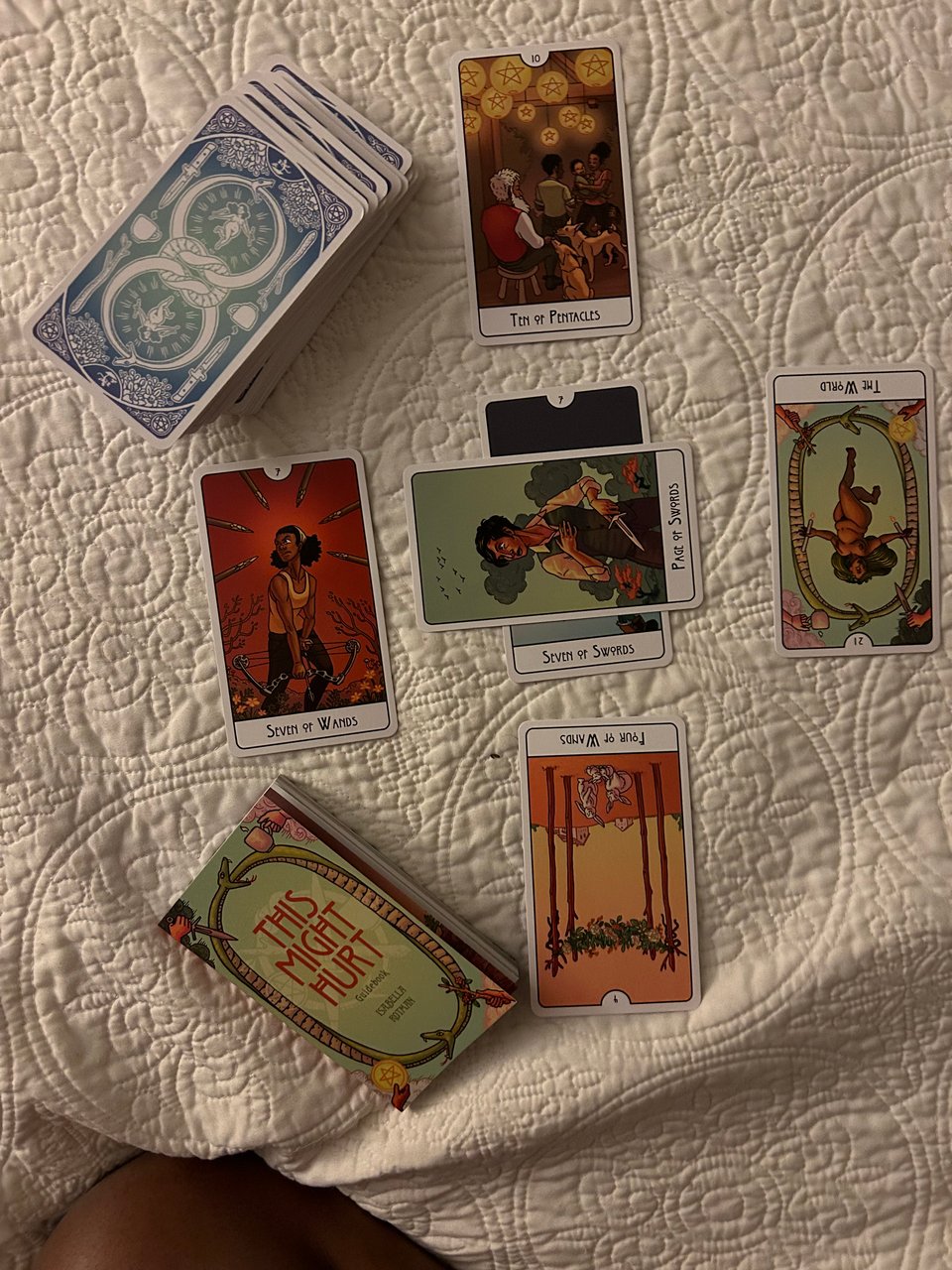 6 tarot cards spread in a cross shape on top of a white comforter.
