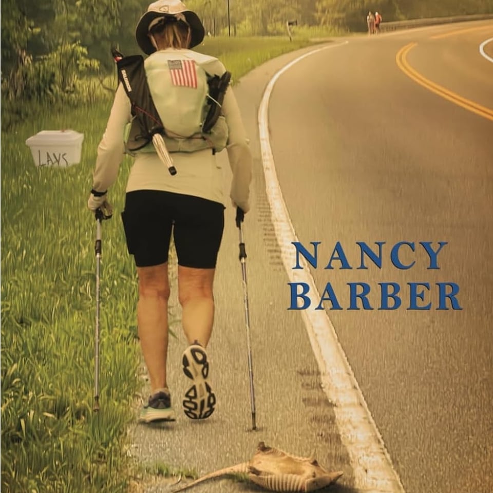 A person walking down the side of a road past a dead armadillo