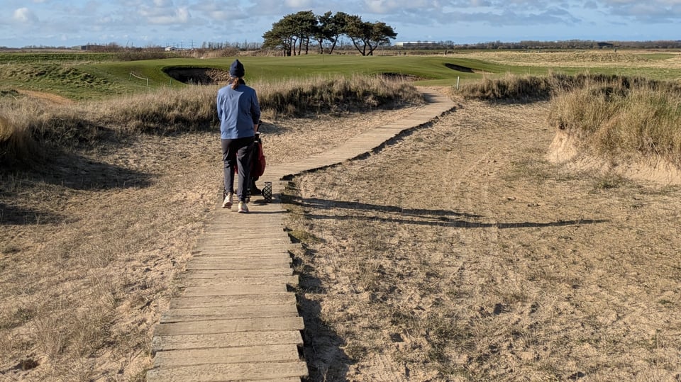 James walking on a sandy wooden sleeper track to the fairway on Prince's