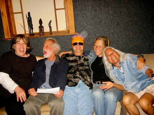 Three women and two scrunched together on a couch smile for the camera.