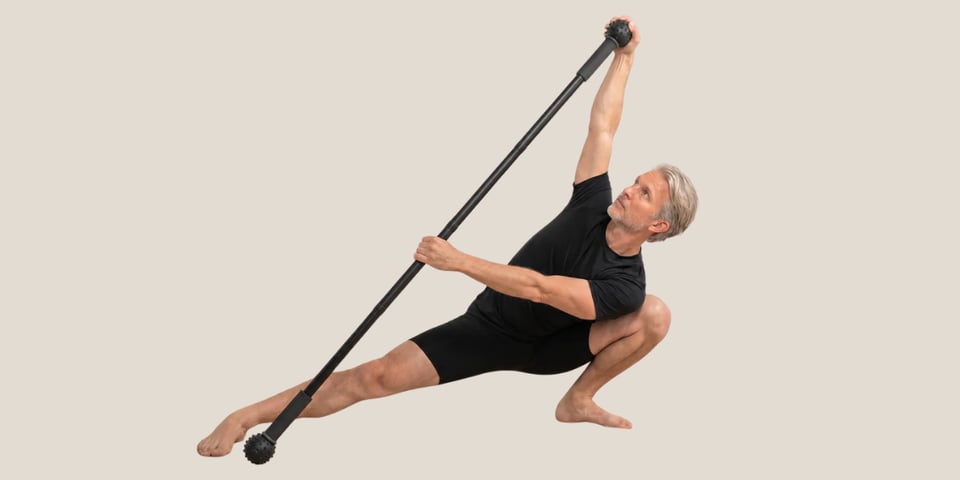 A fit man stretching with a stick.
