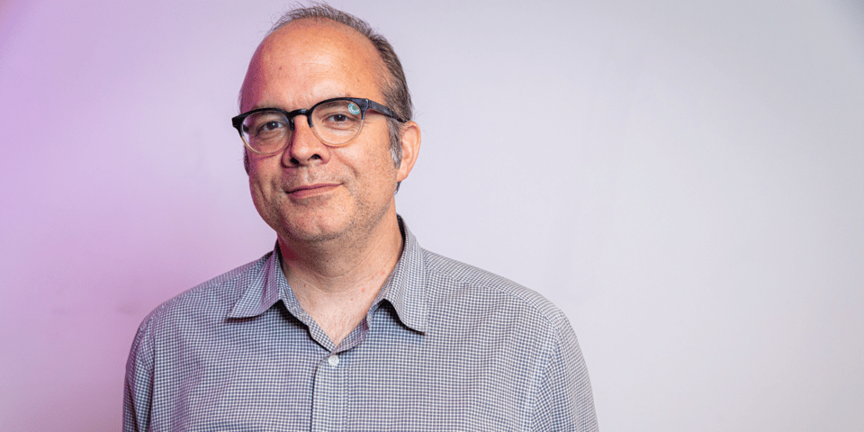 Will Hines. A middle-aged white man against a gradient purple/ white background.