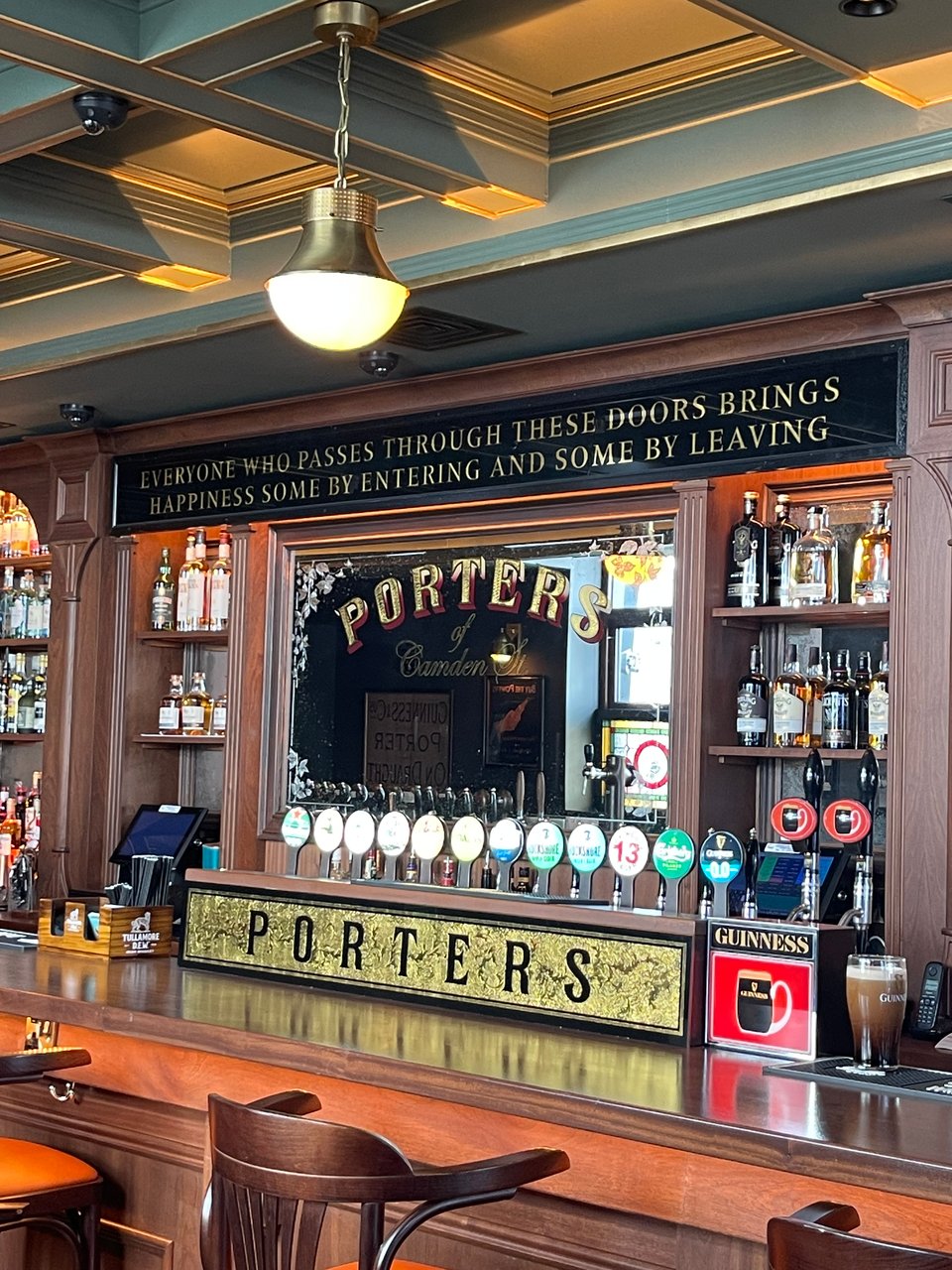 An Irish pub with a gold filigree sign that says PORTERS and a Guiness dark beer sits on the bar.