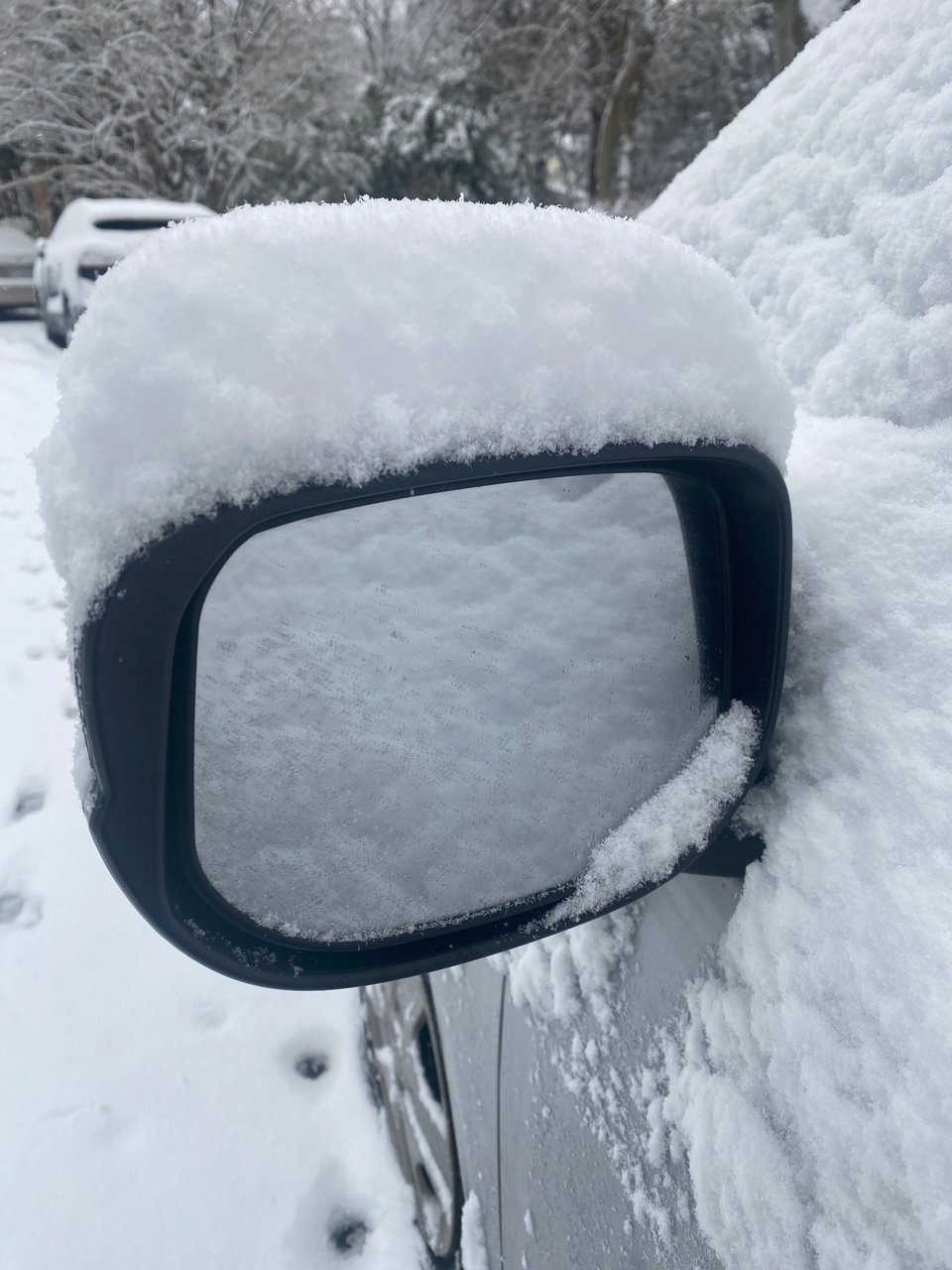 A photo of a car's side-view mirror covered in snow
