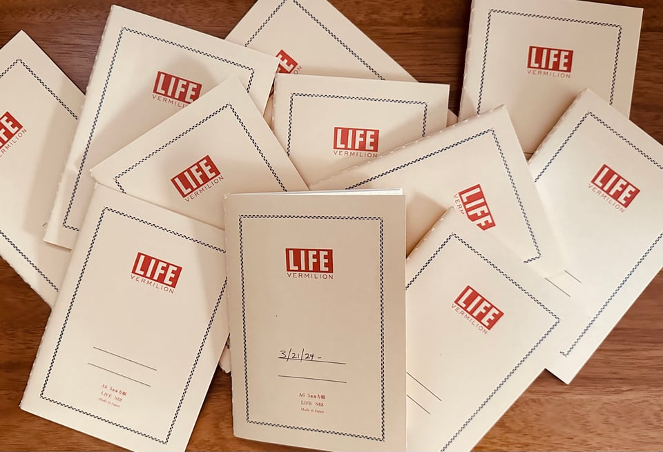 Photo 11 LIFE A6-sized notepads, scattered on a wooden desktop