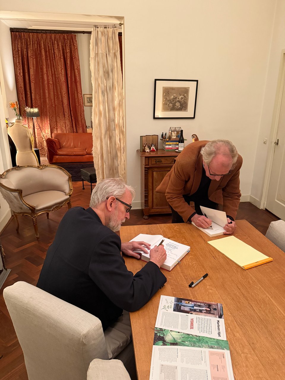 Two men sign their books for each other as gifts.