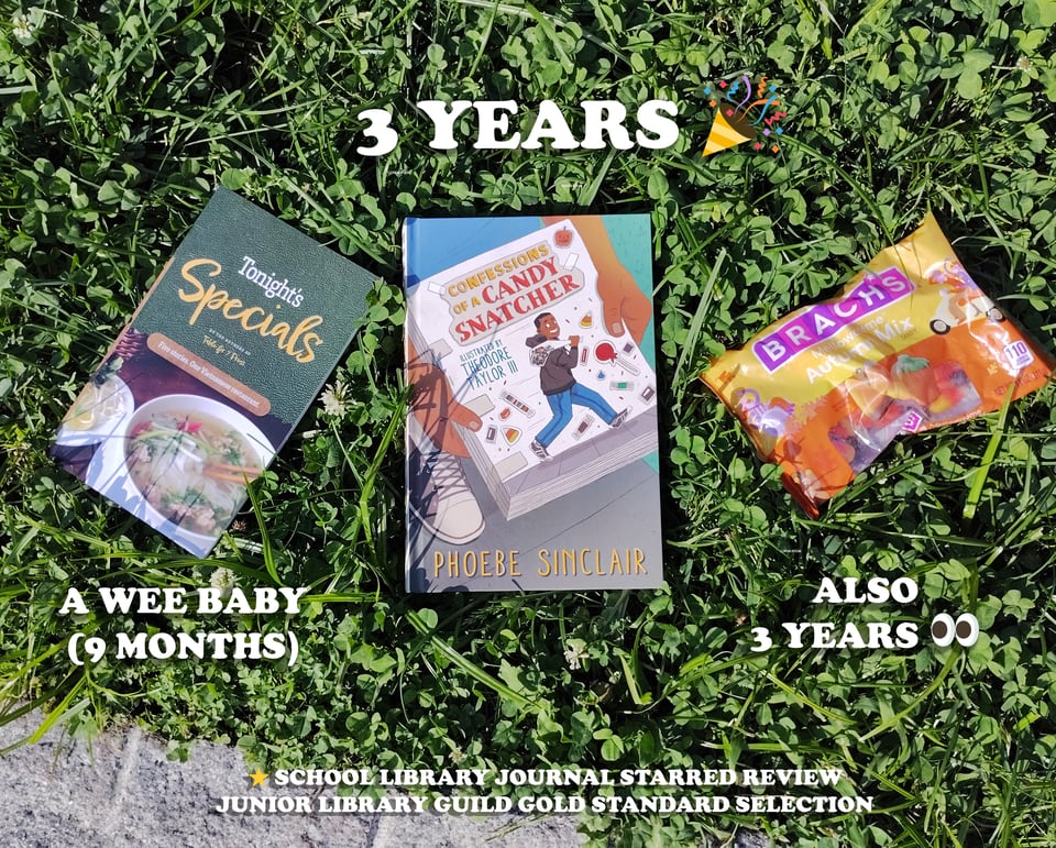 three items lying on a bed of clover and grass, two books and one bag of candy corn