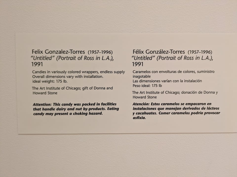 The label for the candy piece, including its artist, title, dimensions, owner, and an allergy warning. These are repeated in Spanish.