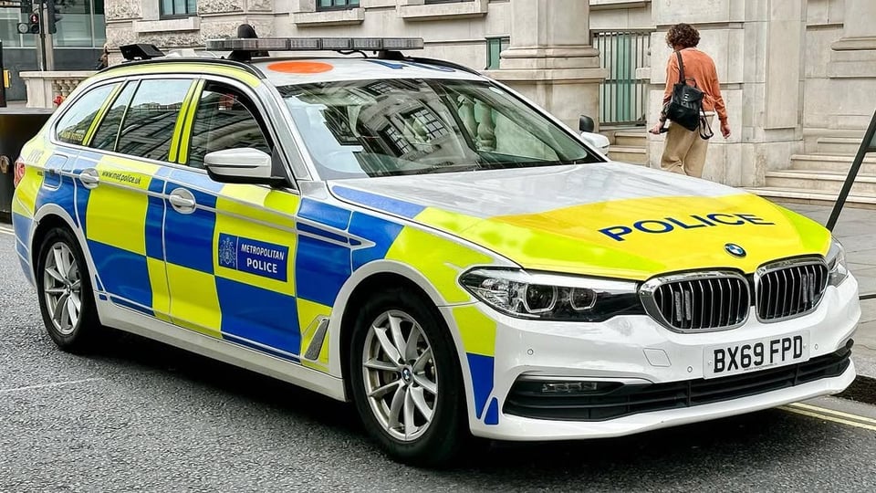 A London Police car, which is a bright green and blue checked vehicle with a roof rack and a hatchback.