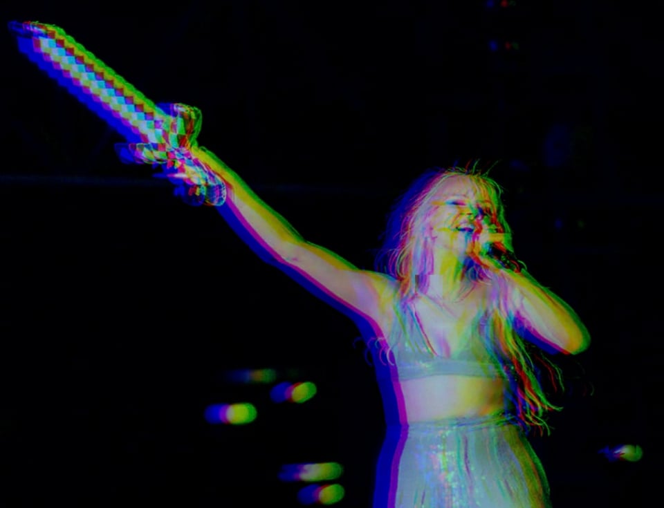 A picture of Carly Rae Jepsen performing onstage. In her left hand is a microphone; in her right, a sword.