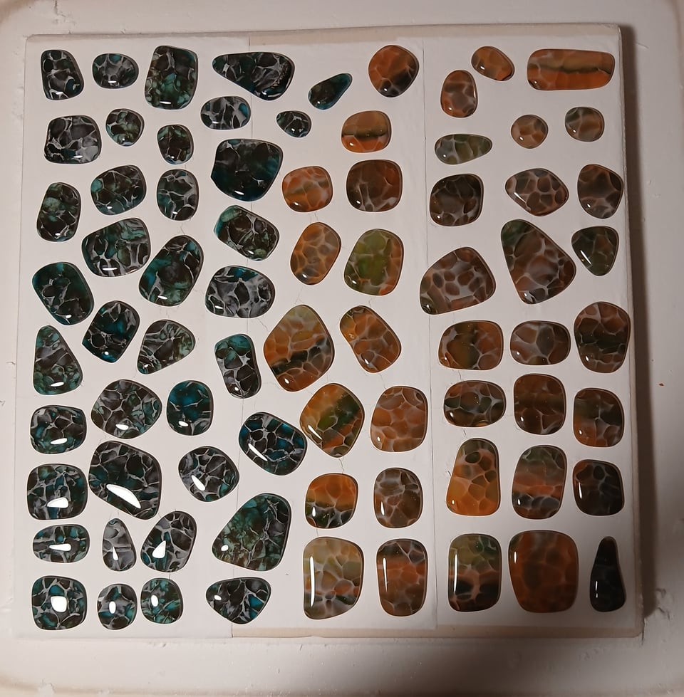 kiln shelf with a bunch of blue/brown glass pieces and a bunch of orange/green glass pieces with a bit of clear frit