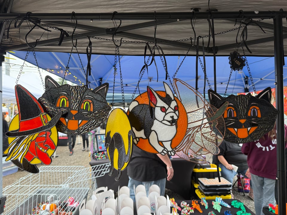 Stained glass circles hanging in a display. The designs are witches, vintage cats and Bunnicula