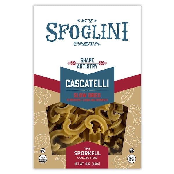 Un paquete de pasta cascatelli. Marca de Sfoglini en la parte superior. Por una ventana transparente en la parte inferior del pack pueden verse los cascatelli del interior, son como pequeños toboganes o cascadas pensados para retener la salsa en su interior