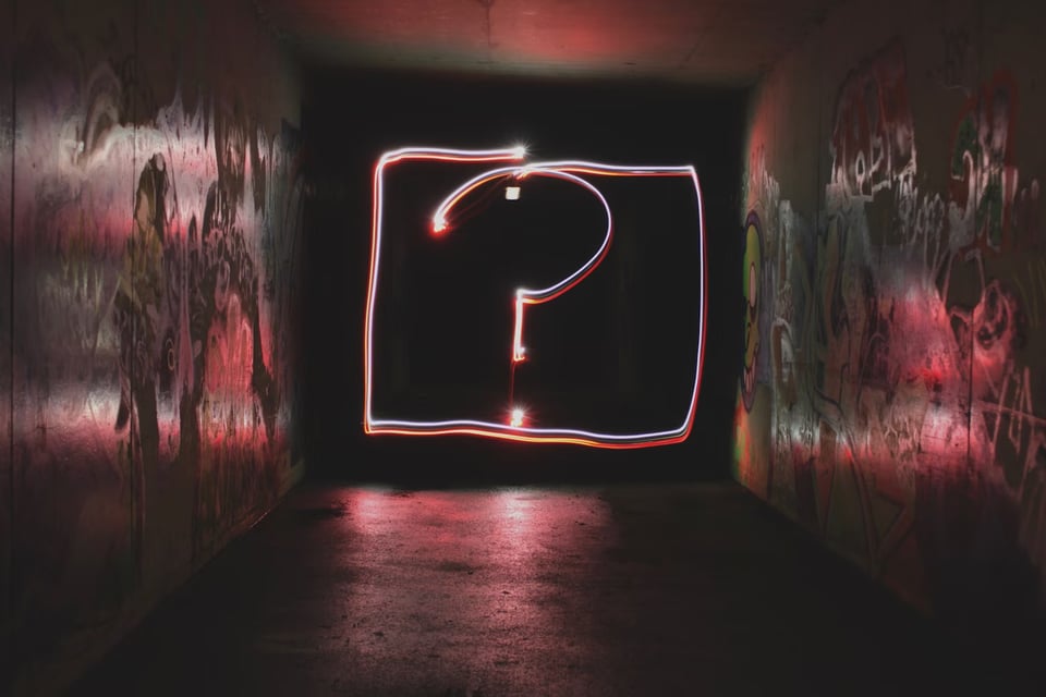 A question mark drawn in light in an alleyway