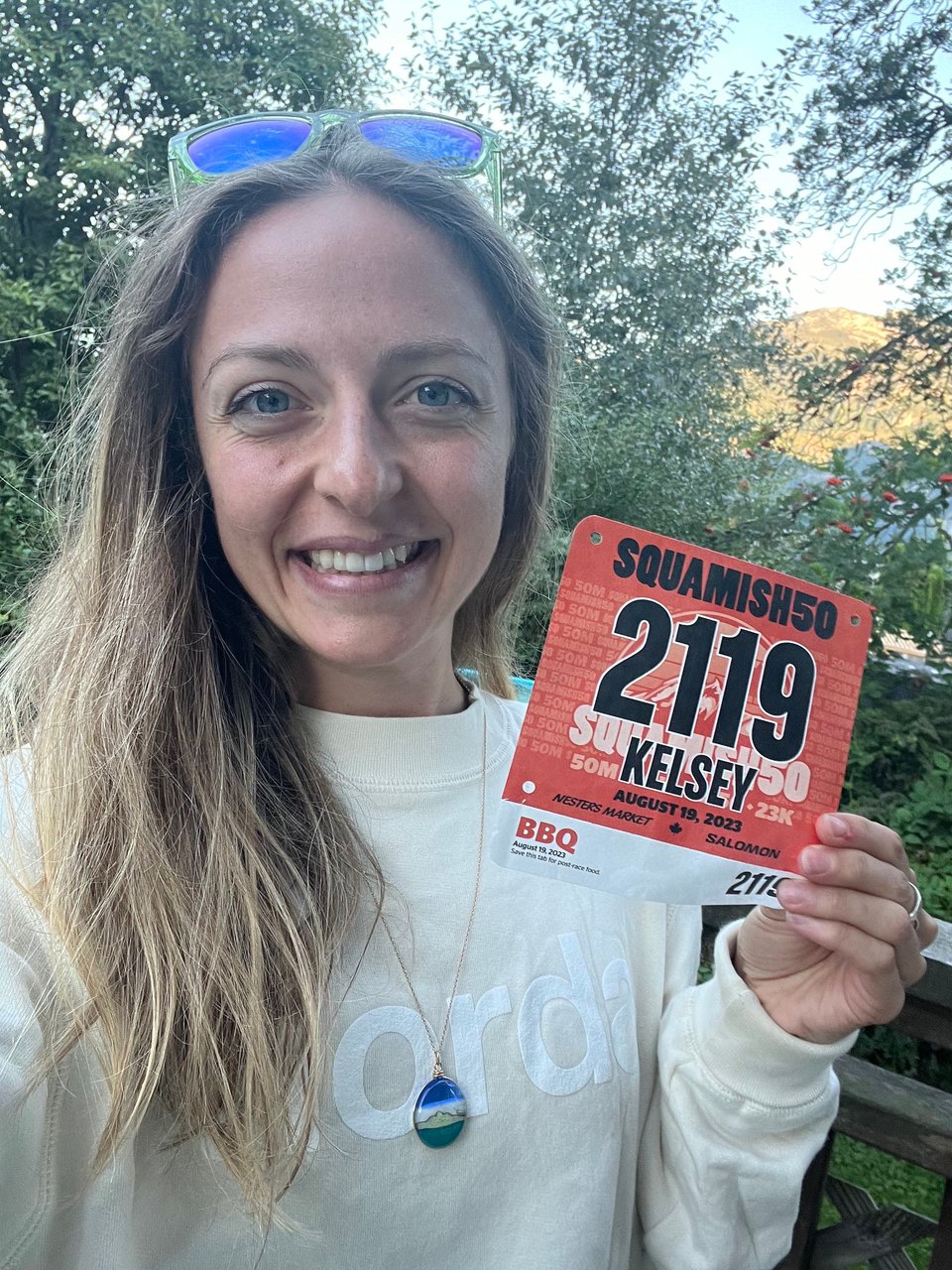 Kelsey holding her bib for the 50 mile race at Squamish. She is smiling and wearing Norda gear.