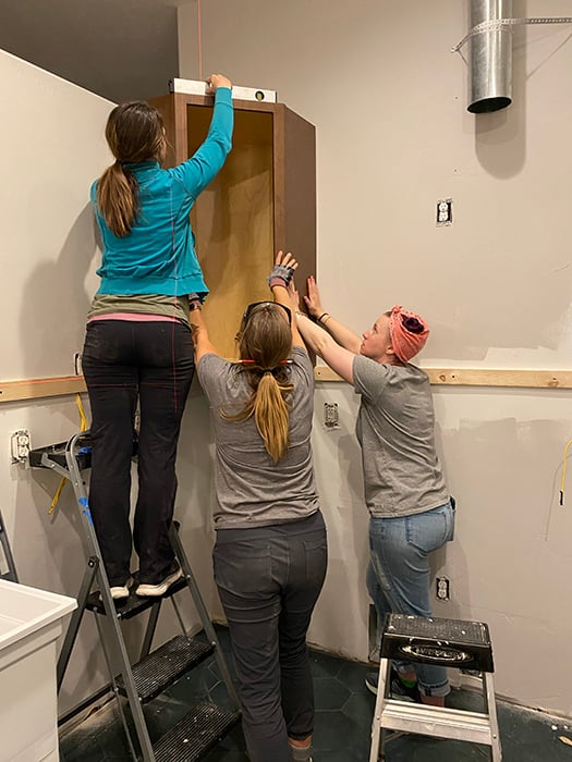 Friends installing kitchen cabinets