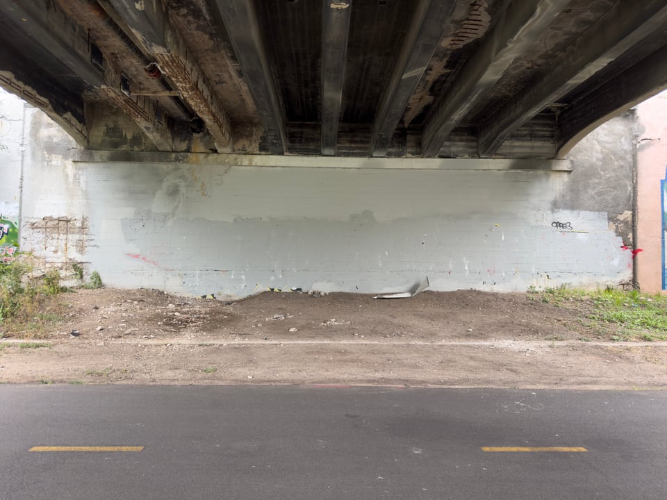 Wall underneath the Grand Avenue Bridge in Minneapolis with dirt and bike path