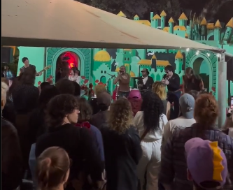 The live band for the musician AroMa performs for a crowd of people.