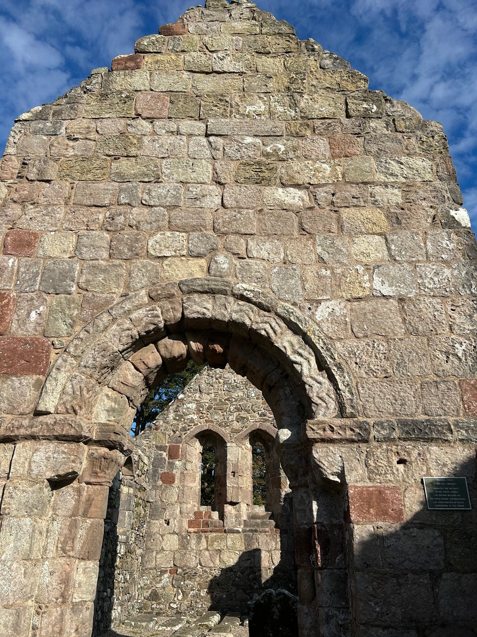 A very old and ruined stone church on the Isle of Bute, showing zig zag decorations over an archway.
