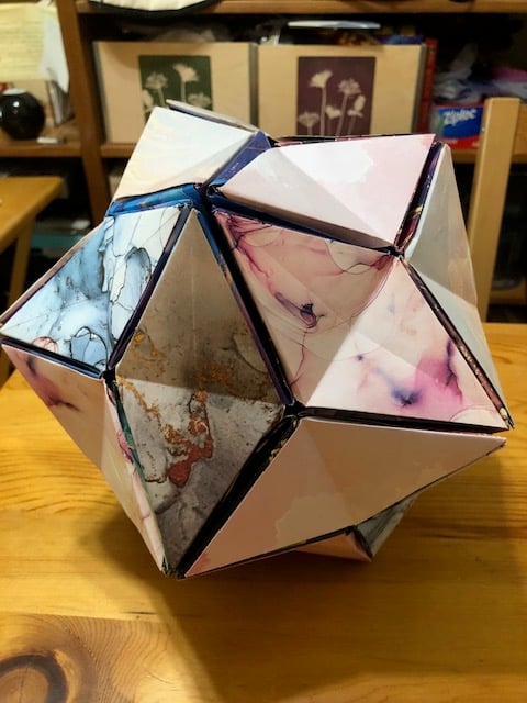 A modular origami model in the shape of a ball made from light colored marbled paper