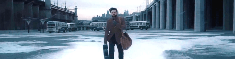 A screenshot from the film Inside Llewyn Davis. It Depicts Oscar Isaacs titular character underdressed in an empty, snowy industrial landscape.