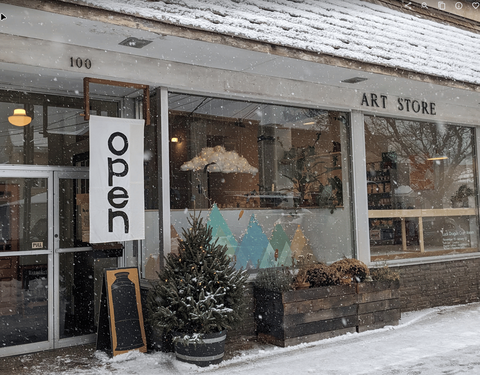 photo of a snowy storefront with a hanging open sign
