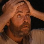 A man with a beard grabbing his head and looking shocked