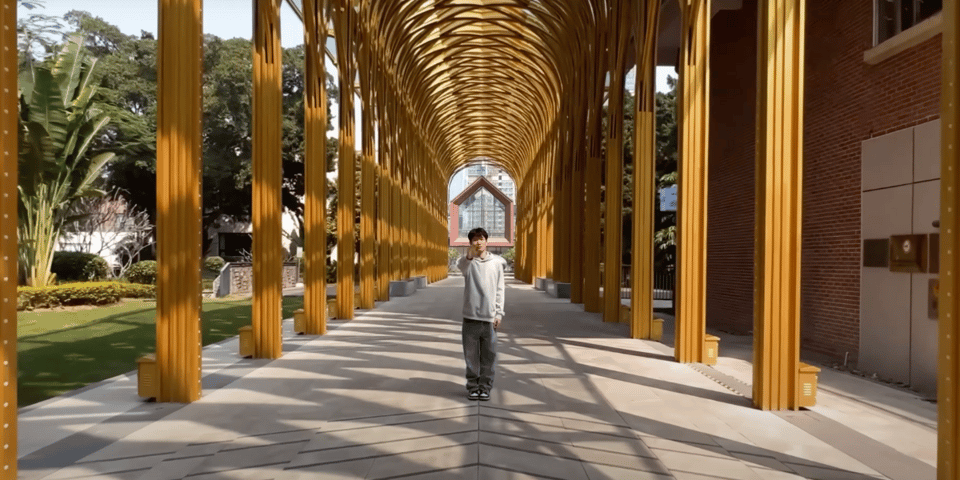An actor stands underneath a yellow lattice arch.