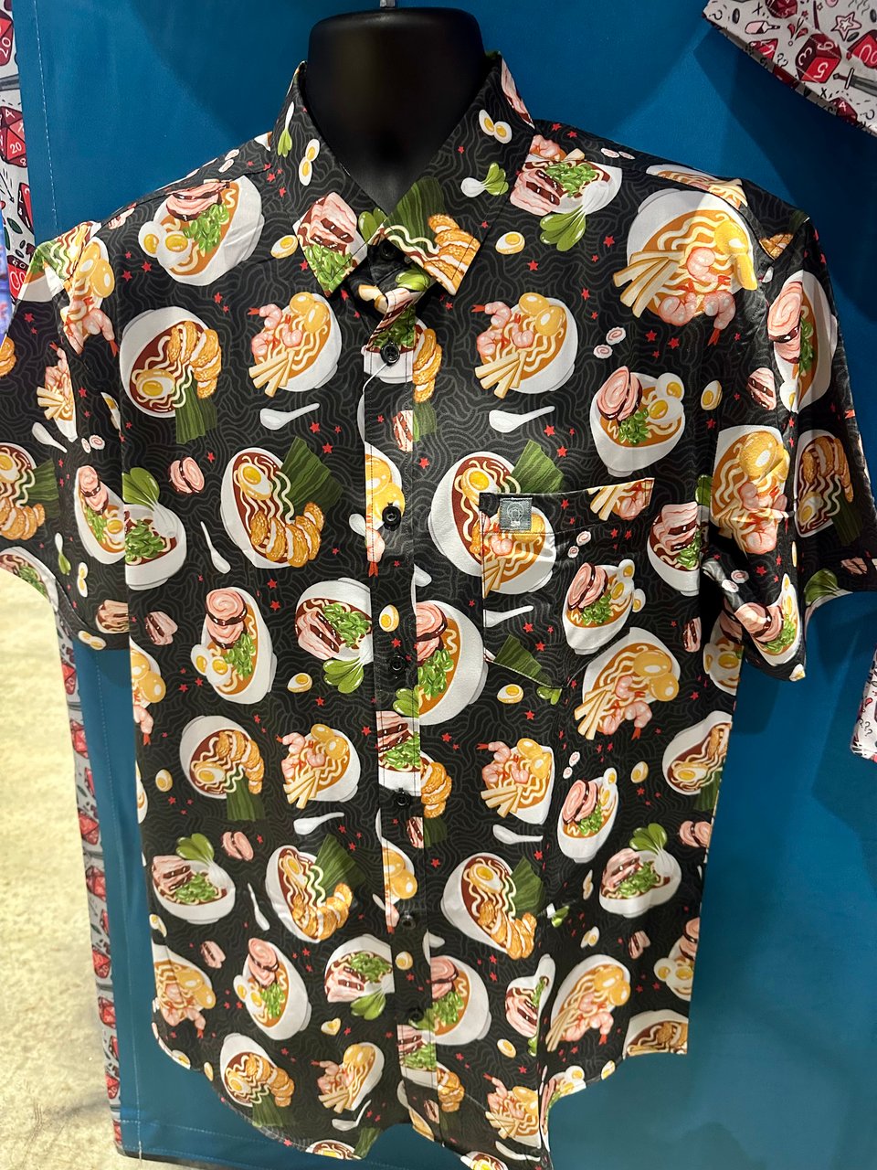 a buttondown shirt in a printed pattern of ramen bowls on a black background