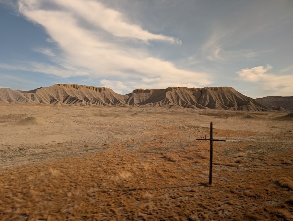 More hills, devoid of grass, with a single abandoned electrical pole in a dry field