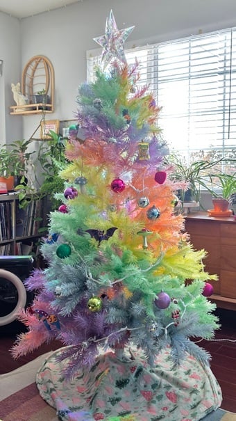 A fake rainbow pastel Christmas tree with colorful ornaments and disco ball ornaments and holographic star