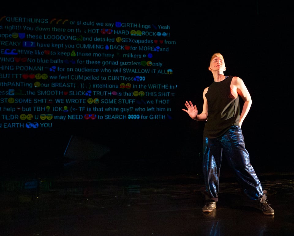Nora stands in a sort of suggestive posture, with one foot out in a sloppy side tendu and one hand showing palm out at the hip, jaw jutted out to the audience. Behind them is a wall of horny dickmoji copypasta text.