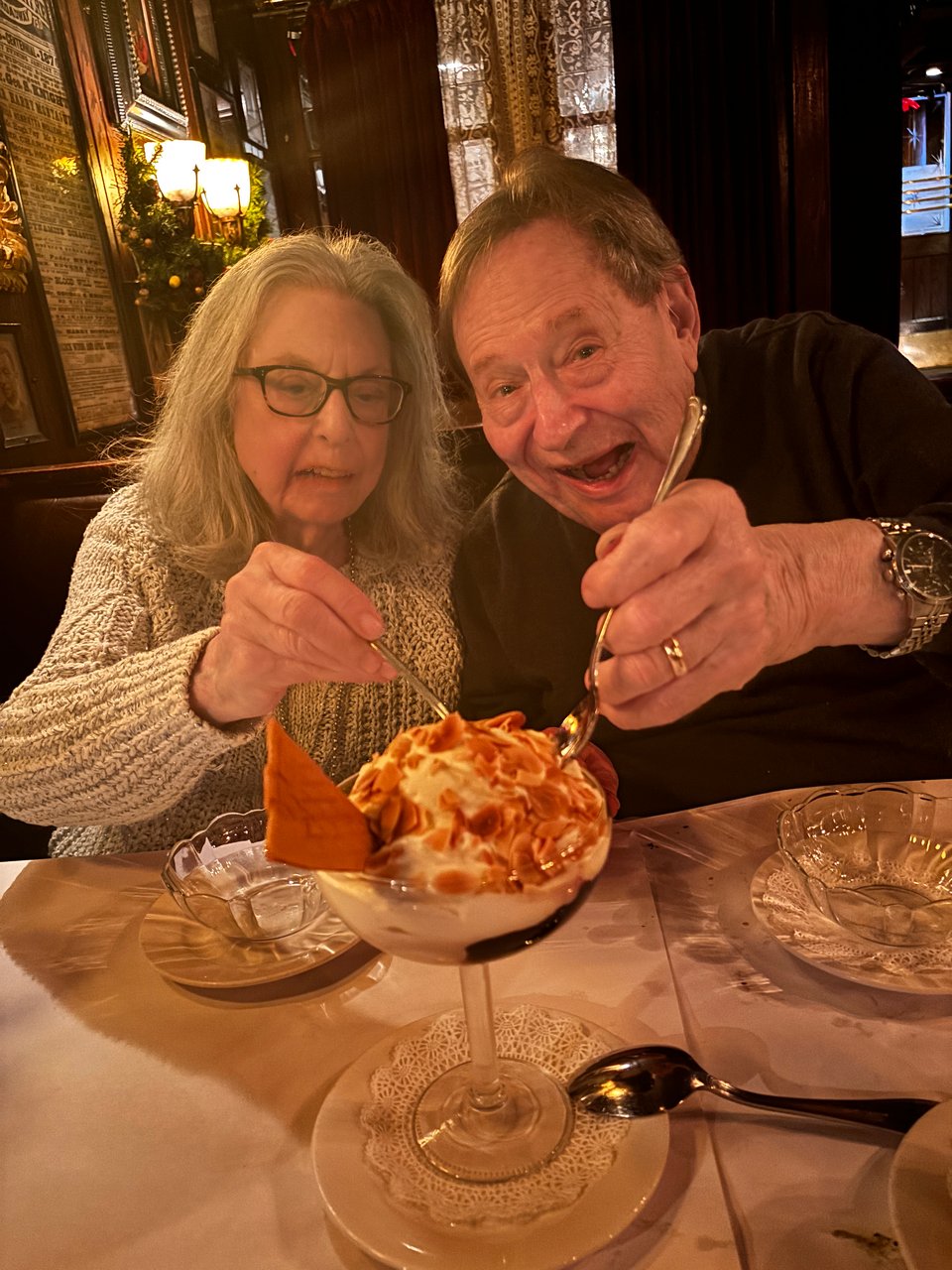 Man and woman affectionately fighting over a large hot fudge sundae at Keens restaurant, 2024