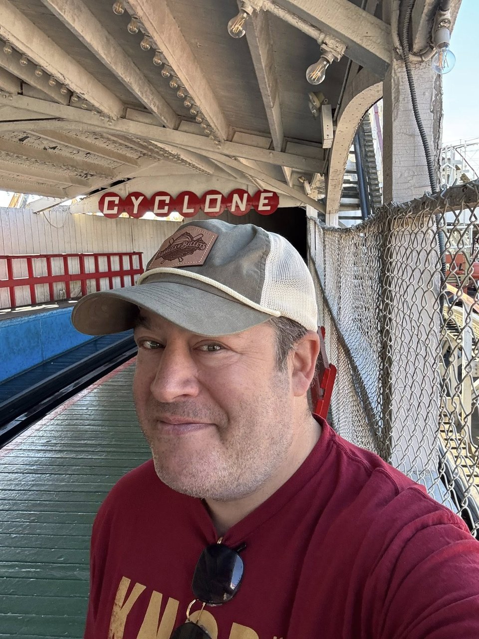 neil in a hat, standing in front of the coney island cyclone in brooklyn