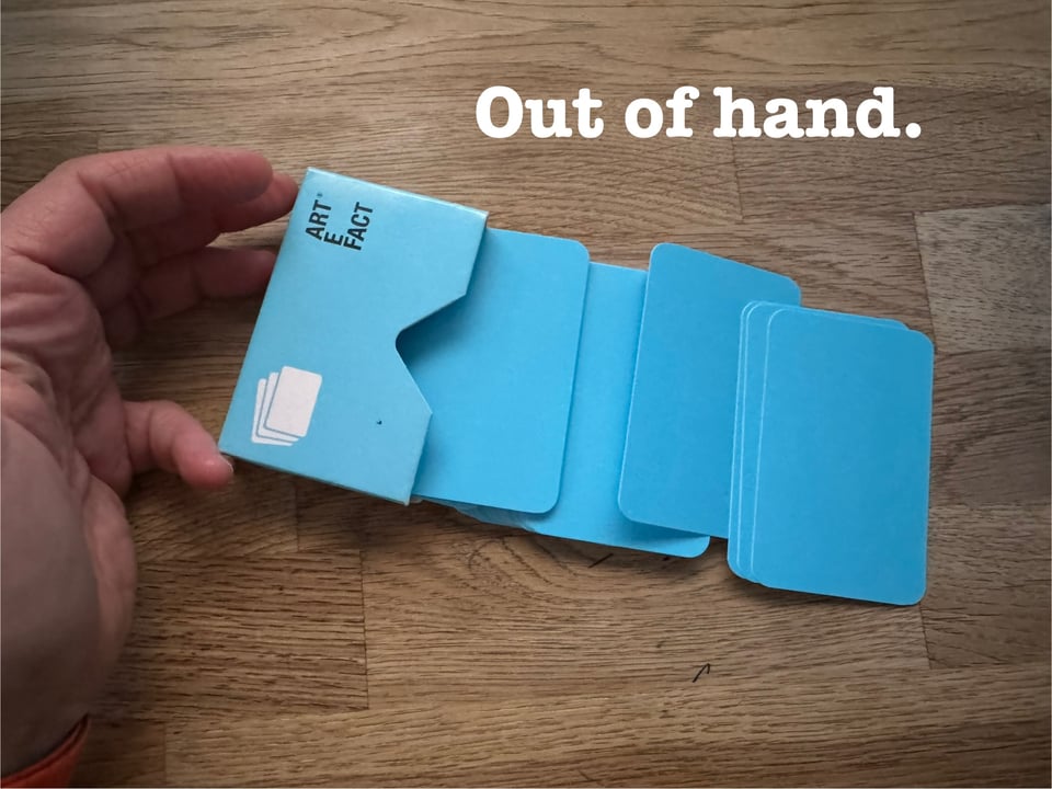 A hand holding some Artefact Cards in their box