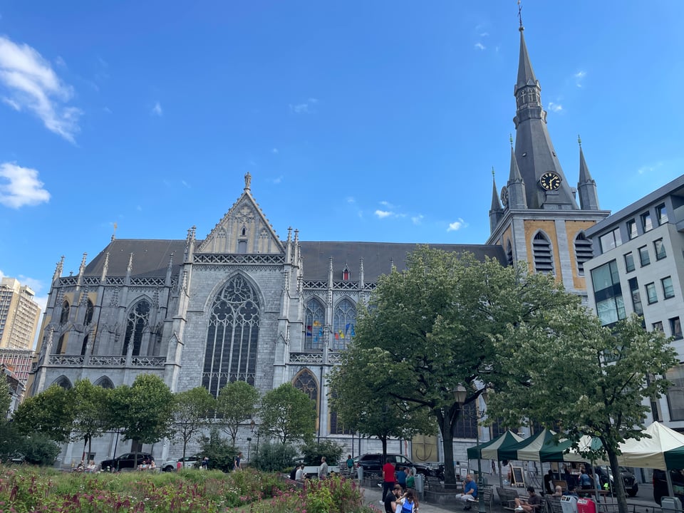 Sude view of a gothic cathedral downtown Liège. The alter is to the left, with the nave behind the city square and the entrance and clock tower to the right.
