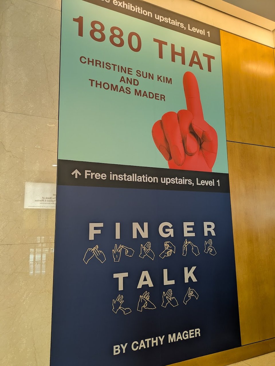 A sign advertising two deaf led exhibitions - 1880 THAT and Finger Talk - as upstairs on Level 1.