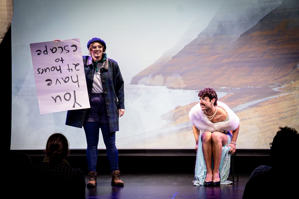 Alayne dressed as a sea-farer, holding a strange message upside down, while Jak watches intently. both in front of a misty cliff backdrop.