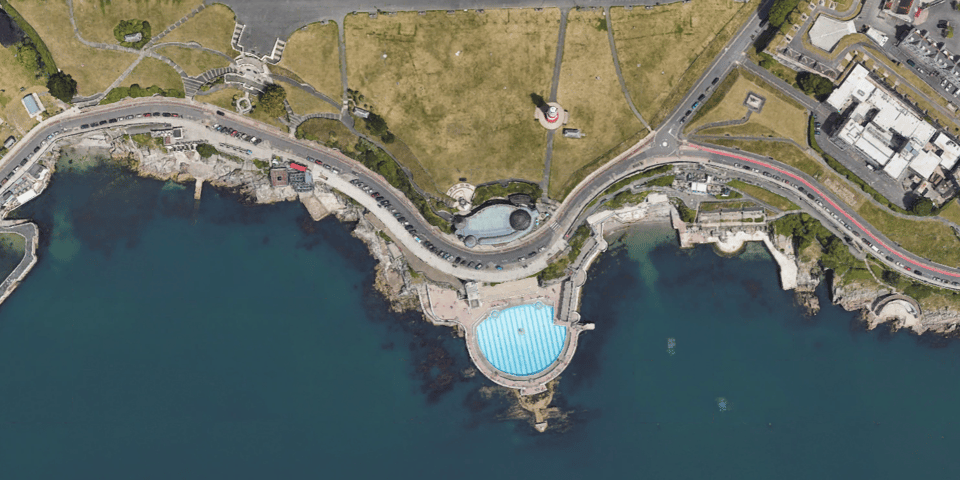 A googlemaps aerial photo of the foreshore, almost exactly as Wibberley had drawn it. It shows the two covers, the curving colonnade and the huge swimming pool with its light blue bright against the dark blue of the sea.