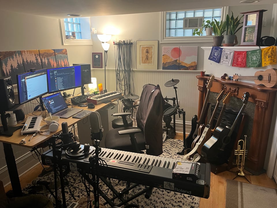 A basement music studio full of instruments including a full size keyboard, trumpet, various guitars, and a ukelele