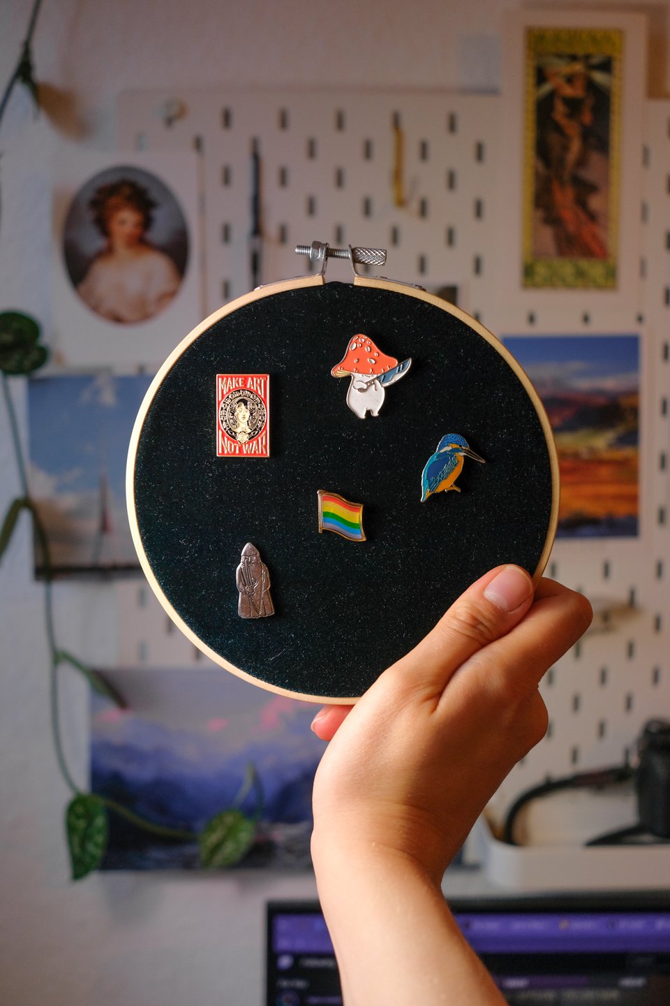 A photo of my hand holding up the embroidery hoop with the fabric, a few pins stuck into the velvet.