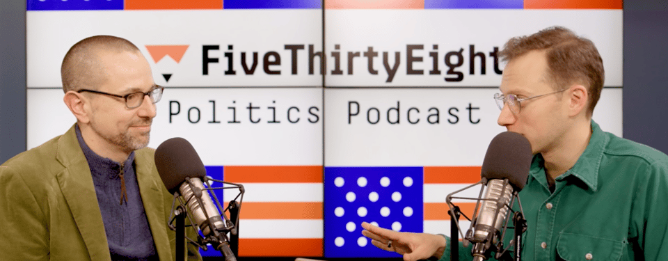 Dan Bouk smirks as Galen Druke asks a question, his hand slightly raised for emphasis