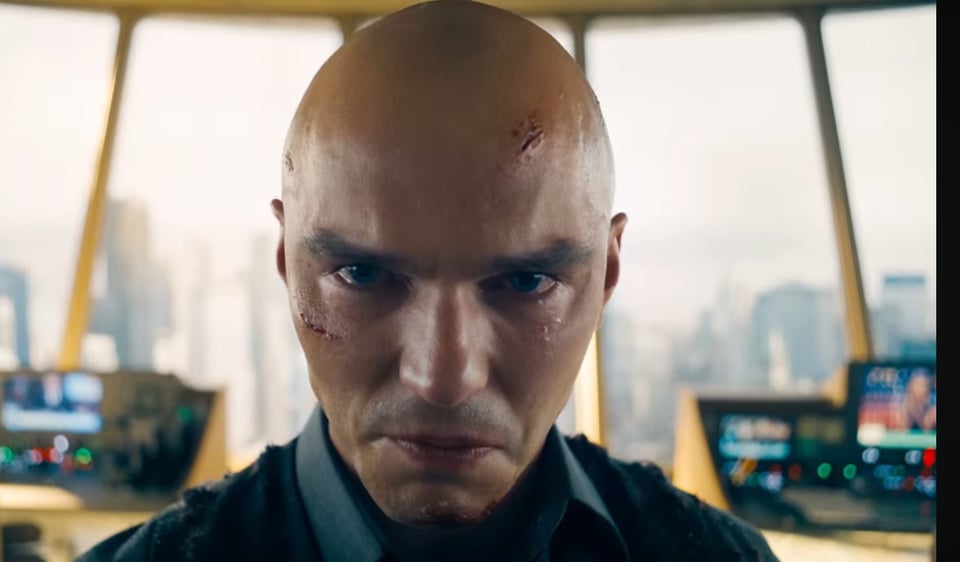 Lex Luthor, a few cuts on his face and head and his suit maybe a bit torn up, glaring directly into the camera.