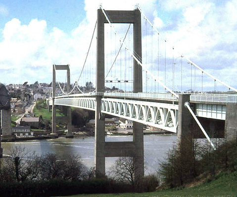 A 1960s suspension bridge high over a river. There are large concrete towers and a suspended metal deck.