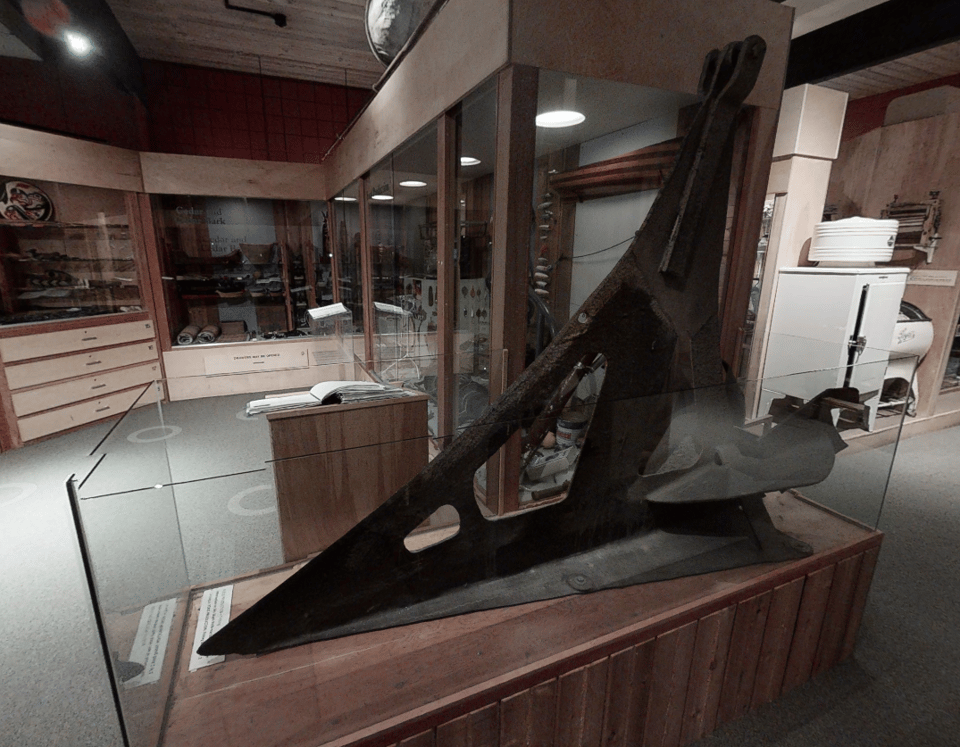 Colour photo of a large curved metal blade sitting inside a dispaly case.