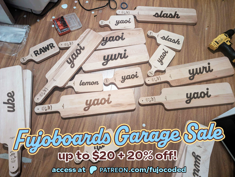 Photograph of a variety of Fujoboards. It is captioned “Fujoboards Garage Sale, up to $20 + 20% off! Access at Patreon.com/FujoCoded”. Words on the boards are “Rawr”, “uke”, “lemon”, “yaoi”, “yuri”, and “slash”. Some of the boards are much smaller. In the background is a drill and bits.
