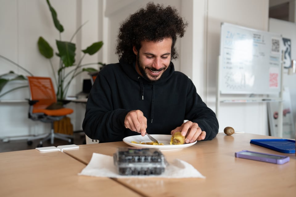 A man attempting to eat a kiwi by unconventional means.