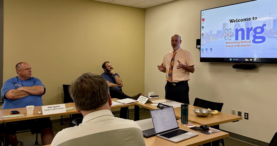 Hugh stands in front of NRG members talking about NY Life.