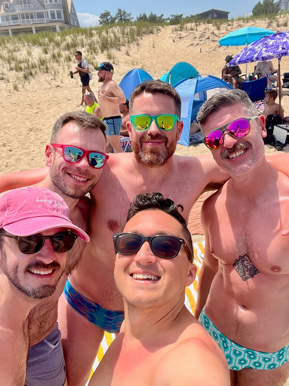 a group of men posing for a selfie on the beach