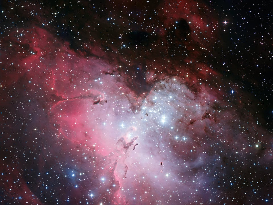 Three-colour composite mosaic image of the Eagle Nebula (Messier 16, or NGC 6611), based on images obtained with the Wide-Field Imager camera on the MPG/ESO 2.2-metre telescope at the La Silla Observatory. At the centre, the so-called “Pillars of Creation” can be seen. This wide-field image shows not only the central pillars, but also several others in the same star-forming region, as well as a huge number of stars in front of, in, or behind the Eagle Nebula. The cluster of bright stars to the upper right is NGC 6611, home to the massive and hot stars that illuminate the pillars. The “Spire” — another large pillar — is in the middle left of the image.